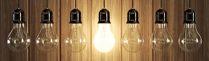 Row of seven lightbulbs with one lit bulb