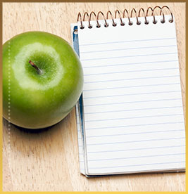 Notebook and apple on wood background