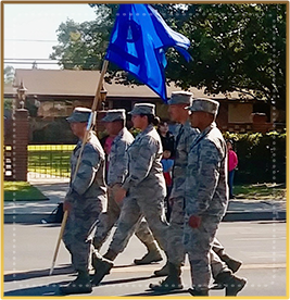 ROTC students marching outside with blue flag