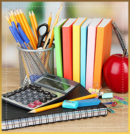 Notebooks, pens, pencils, a calculator, an apple, paperclips and erasers on a wood table