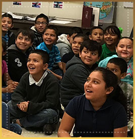 Students sit on the floor and smile