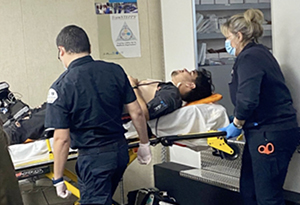 EMT teachers pushing student volunteer on a gurney